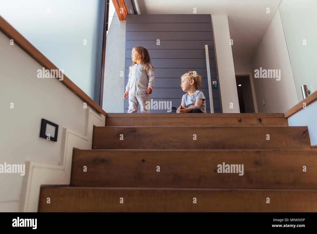 Bruder und Schwester sitzen auf der Treppe und außerhalb. Kinder zu Hause weg suchen nach etwas interessant. Stockfoto