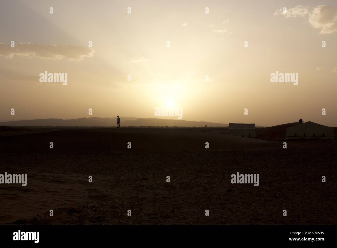 Einer Person, die auf einer Sanddüne beobachten Sie den Sonnenuntergang über der Wüste Zagora, Marokko Stockfoto
