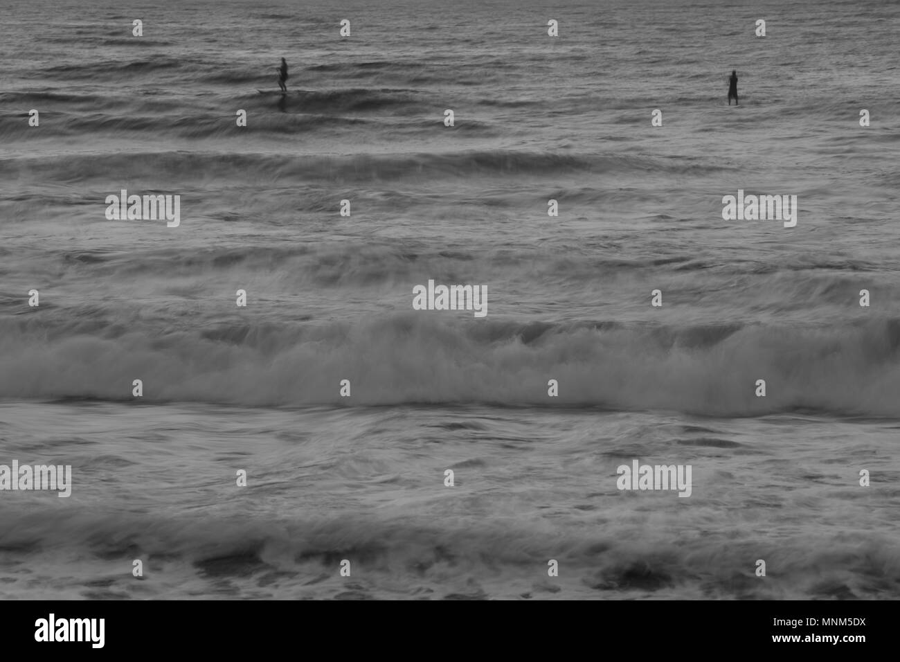 Zwei erwachsene Männer auf Stand up Paddle Boards genießen Sie ruhige See Bedingungen hinter brechenden Wellen Stockfoto