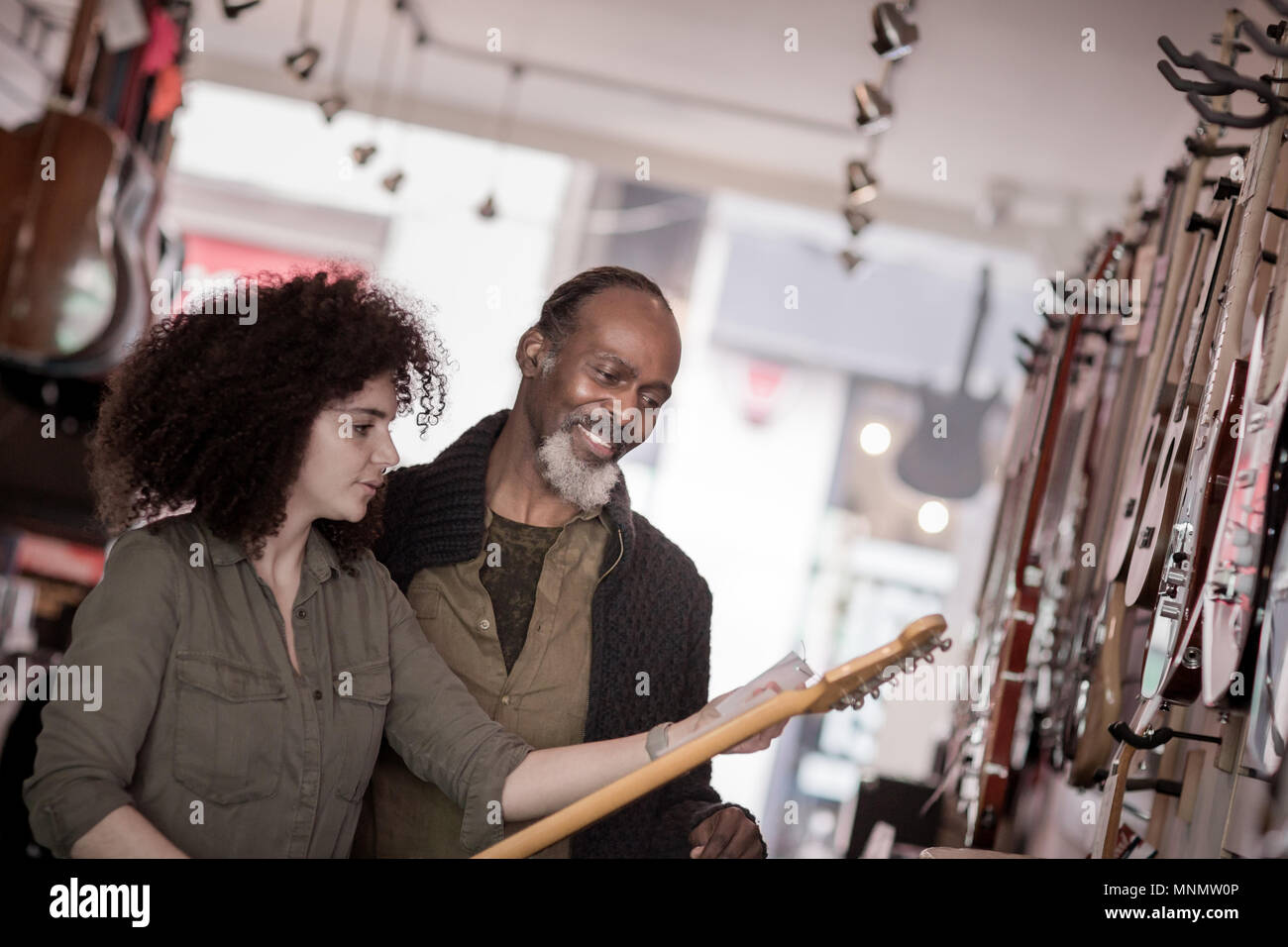 Inhaber kleiner Unternehmen hilft Kunden in einem Guitar Store Stockfoto