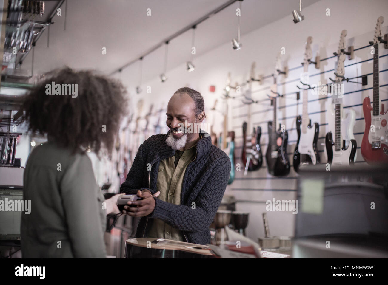 Ältere männliche Zahlen in einem Guitar Store mit Kreditkarte Stockfoto