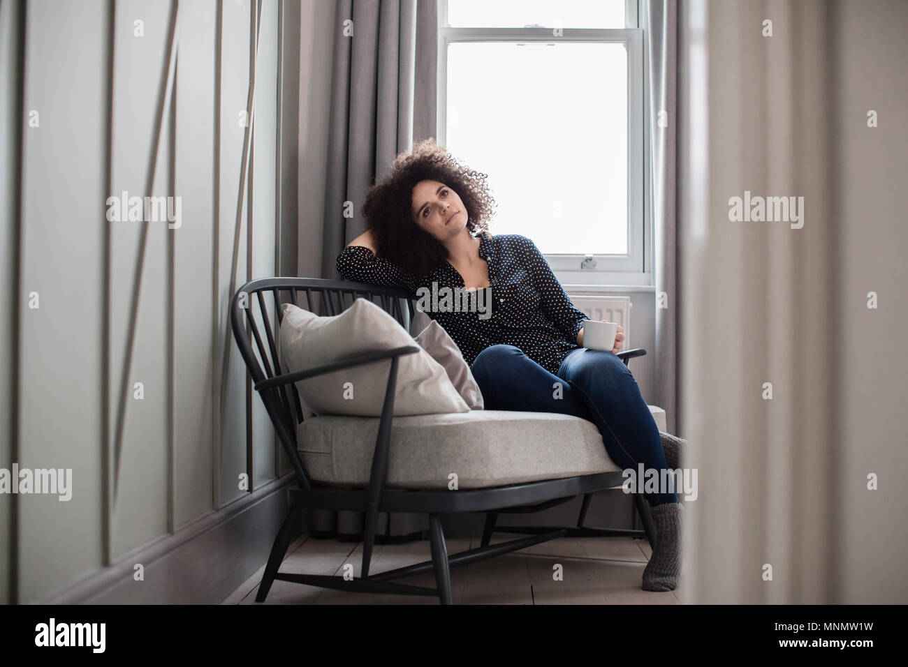 Junge erwachsene Frau entspannt zu Hause mit Kaffee Stockfoto