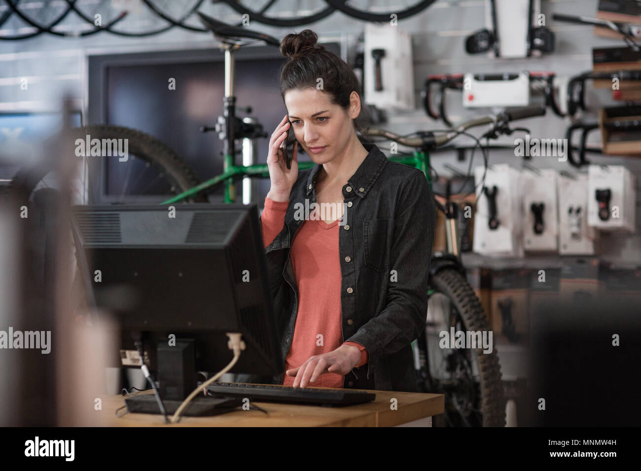 Inhaber kleiner Unternehmen auf Telefon und Computer in einem Geschäft Stockfoto