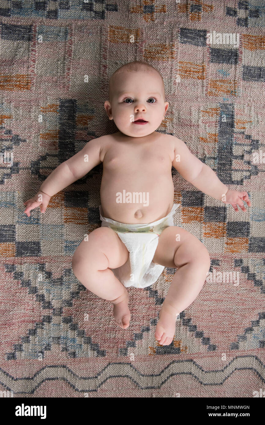 Baby (12-17 Monate) liegen auf dem Teppich Stockfoto