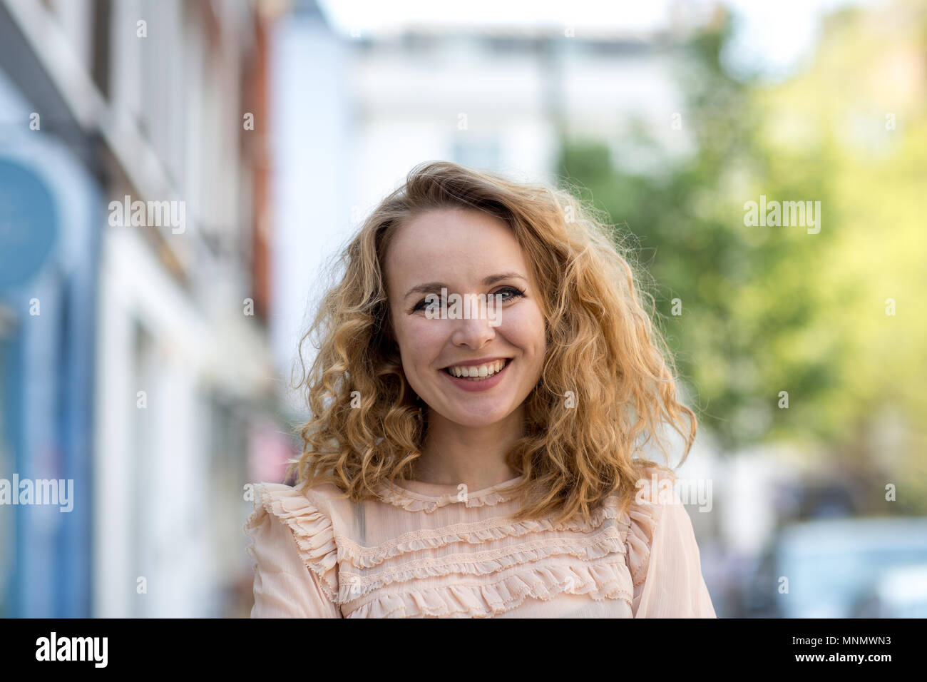 Erwachsene Frau lächelnd im Freien in der Stadt Stockfoto