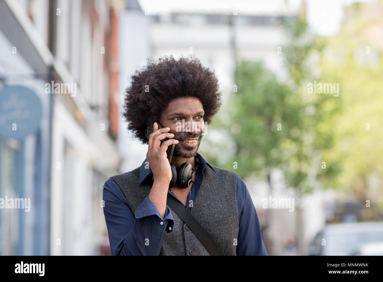 Afrikanischer Amerikanischer Mann zu Fuß und auf dem Smartphone in der Stadt Stockfoto
