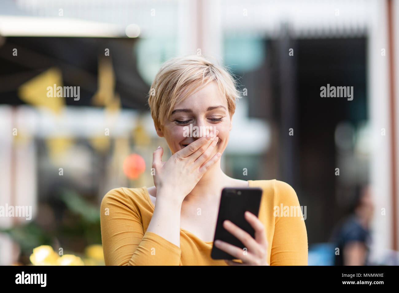 Junge Erwachsene Weibchen an Smartphone lachen Stockfoto