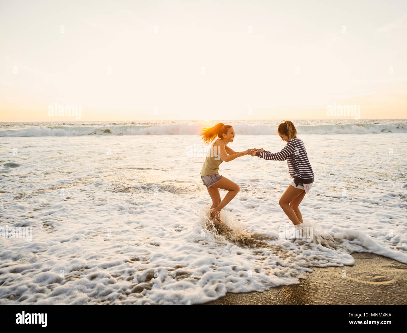 Mutter und Tochter springen in Wellen Stockfoto