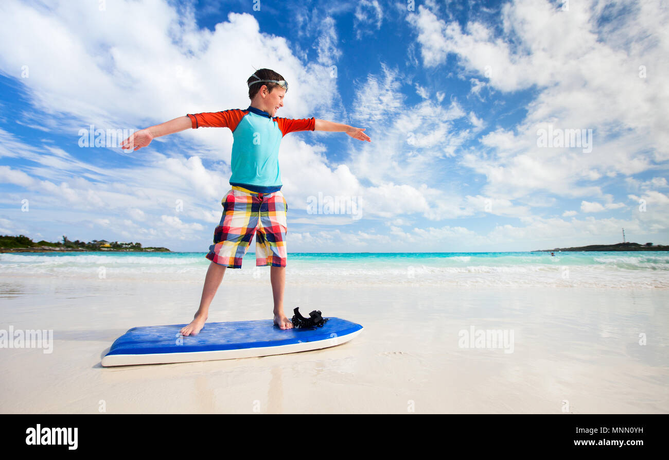 Kleinen Jungen im Urlaub Spaß lernen Surfen am Strand Stockfoto