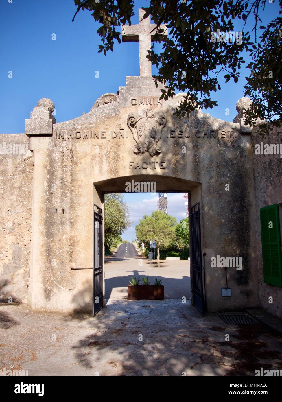 Historischen Eingang zu einer Kirche Hof durch ein Kreuz über eine offene Tür mit Blick auf eine geteerte Straße im Hintergrund überragt Stockfoto