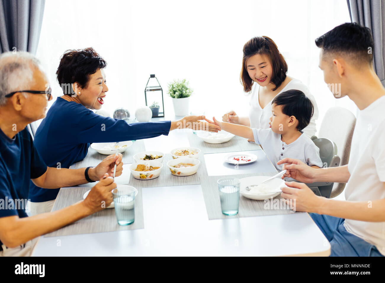 Gerne asiatische Großfamilie Abendessen zu Hause voller Lachen und Glück Stockfoto