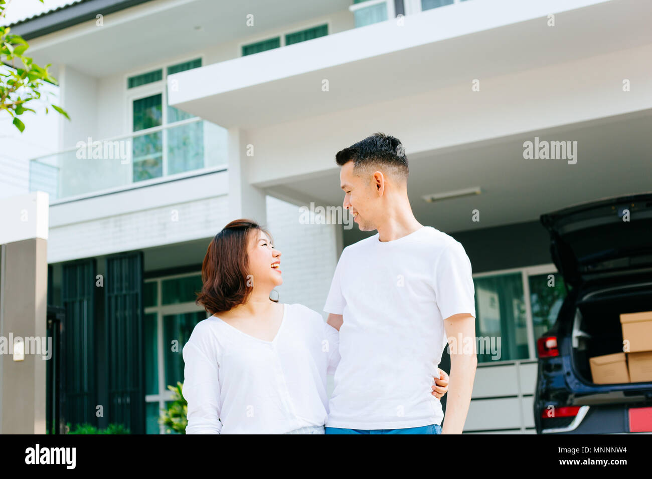 Asiatische Paar stand vor ihrem neuen Haus. Brautpaar Familie gerade im neuen Haus und Auto Kisten verschoben Stockfoto