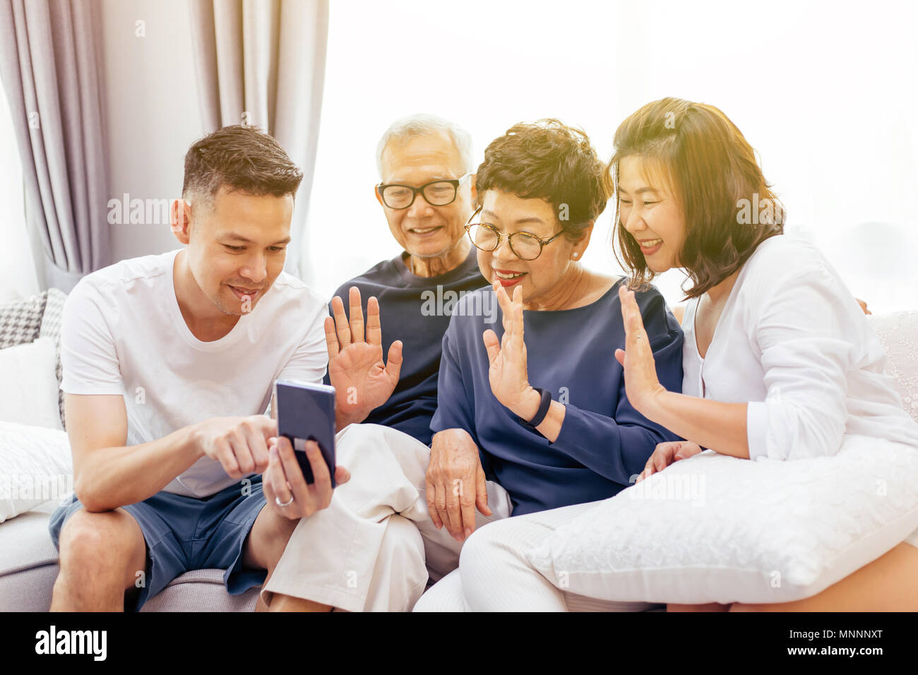 Asiatische Familie mit erwachsenen Kindern und älteren Eltern Videoanruf und winkt für den Anrufer zu Hause Stockfoto