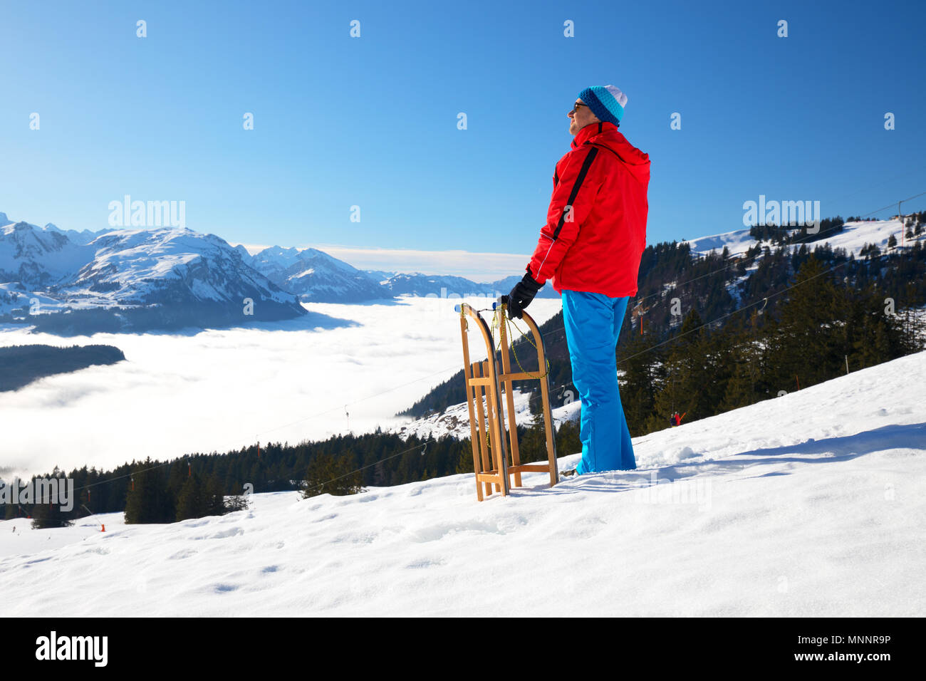 Jungen attraktiven Mann bereit, Rodeln in den Schweizer Alpen im Winter Ferien zu gehen. Stockfoto