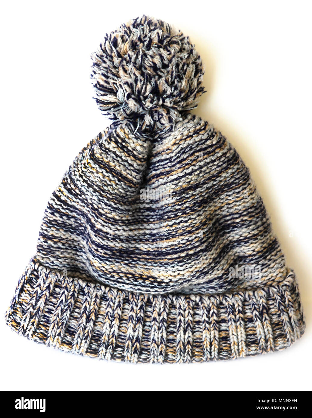 Gestrickte Mütze mit pompon von bunten Fäden auf weißem Hintergrund Stockfoto