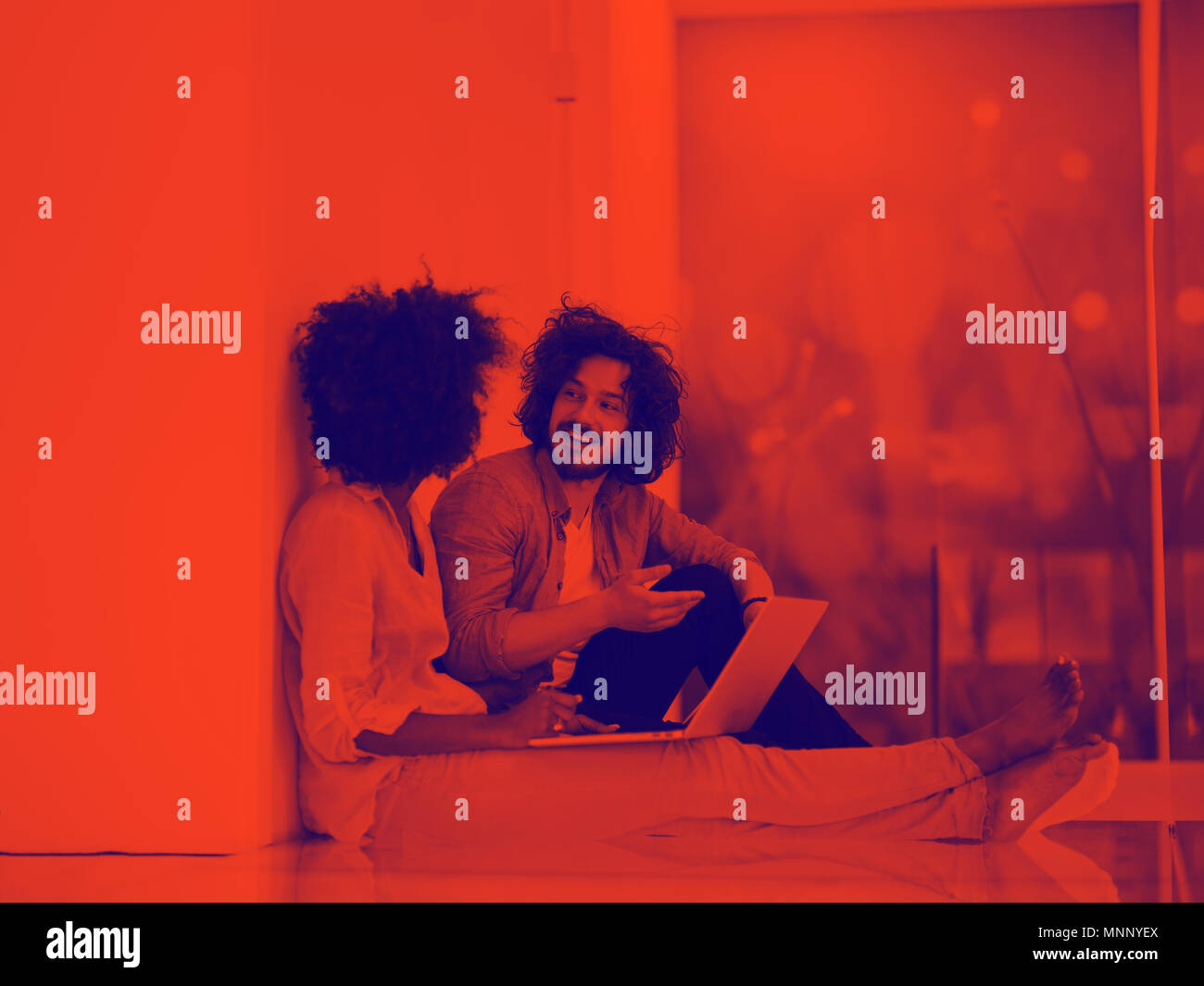 Junge schöne multiethnischen paar mit einem Laptop und Online-shopping auf dem Boden sitzend Stockfoto