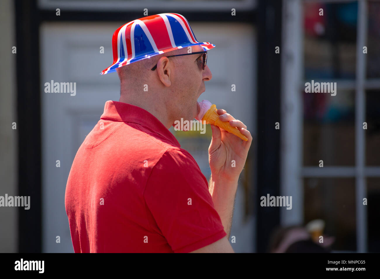 Ein Mann, der einen Union Jack Hut trägt und bei einer Vorführung der königlichen Hochzeit von Prinz Harry und Meghan Markle ein Eis isst. Ringwood, Hampshire, England, Großbritannien, 19.. Mai 2018. Stockfoto