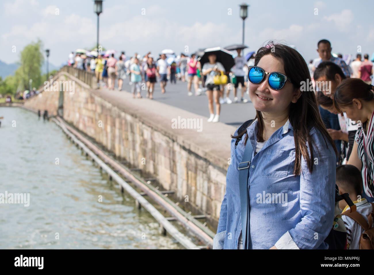 Ein langes Haar chinesischen Frau in Schatten stellen und an einem Duanqiao Canxue Brücke in West Lake, Hangzhou, China lächelnd. Stockfoto