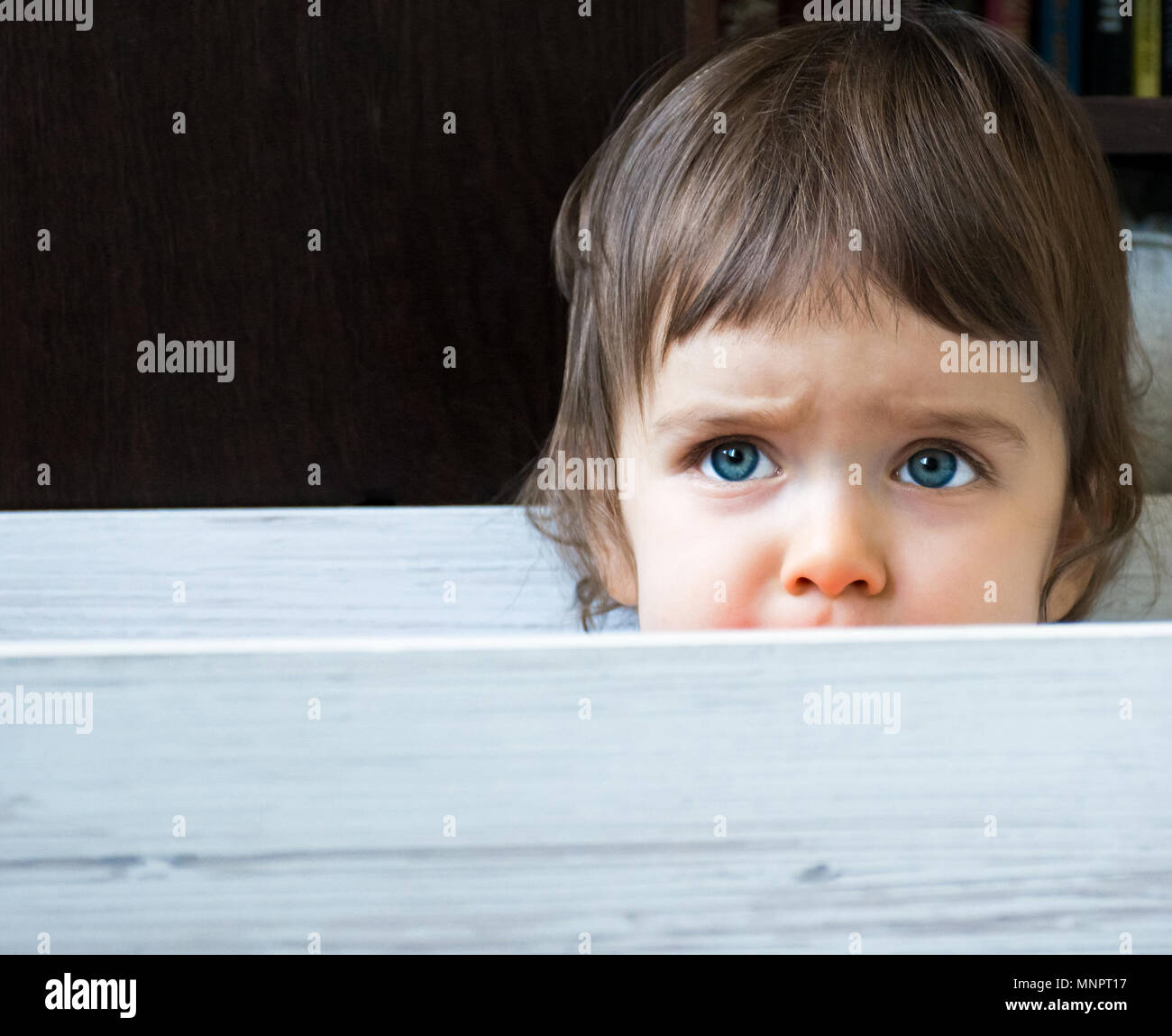 In der Nähe der schöne blaue Augen Baby Kind sitzen und versteckt sich in einer Box neugierig. Kopieren Sie Platz. Stockfoto