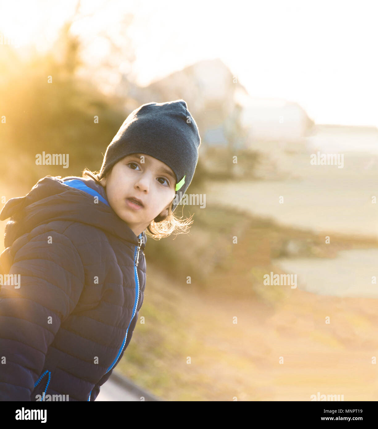 Schöner Rücken beleuchtet Junge Kind neugierig über die Schulter an kalten sonnigen Winter oder Herbst Tag. Kopieren Sie Platz. Stockfoto