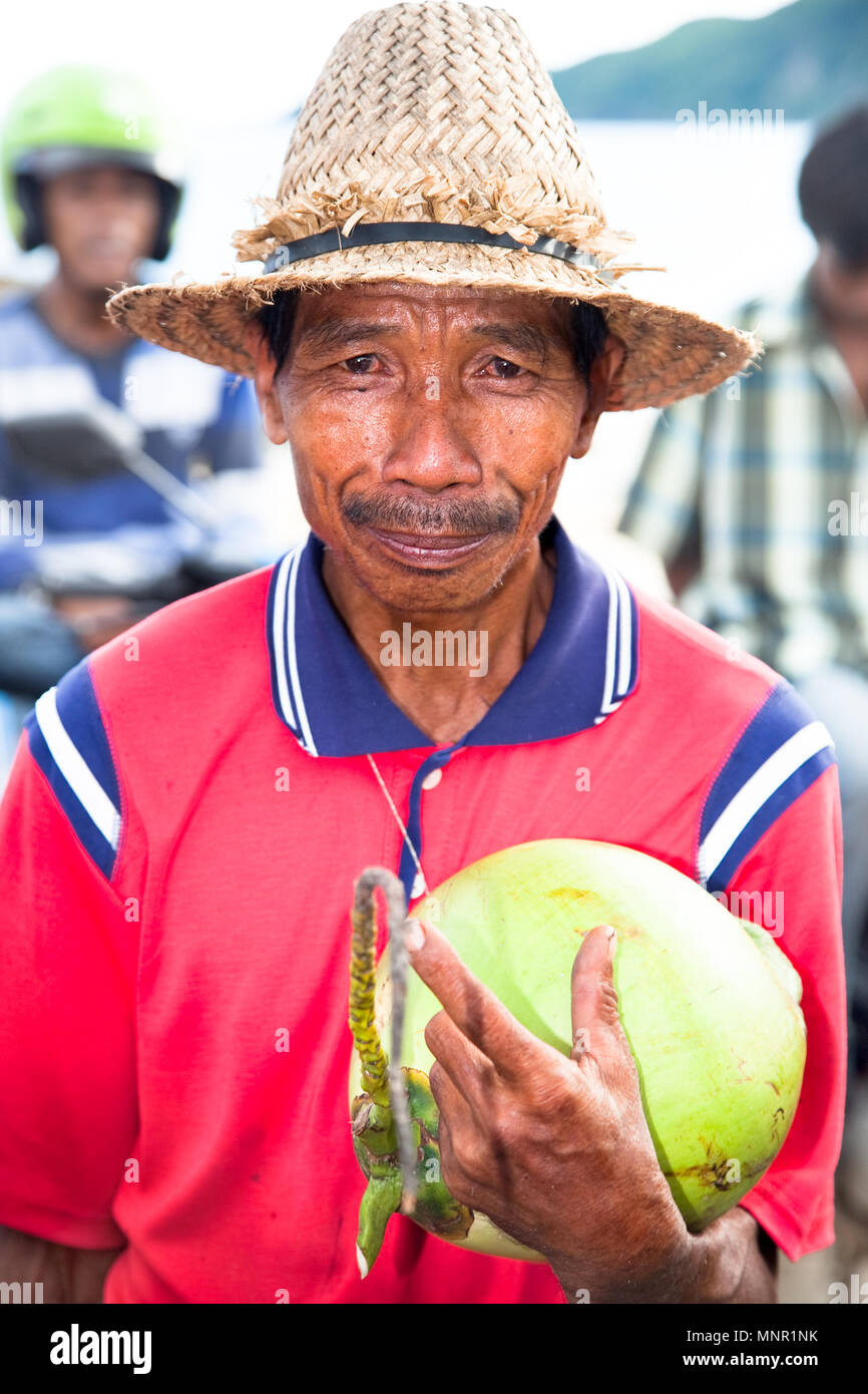 LOMBOK, Indonesien - 11. Februar: arme Mann mit Strohhut Verkauf eine Kokosnuss auf Februar 11,2012 Lombok, Indonesien. Kokosnuss Wasser ist beliebtes Getränk in der Stockfoto