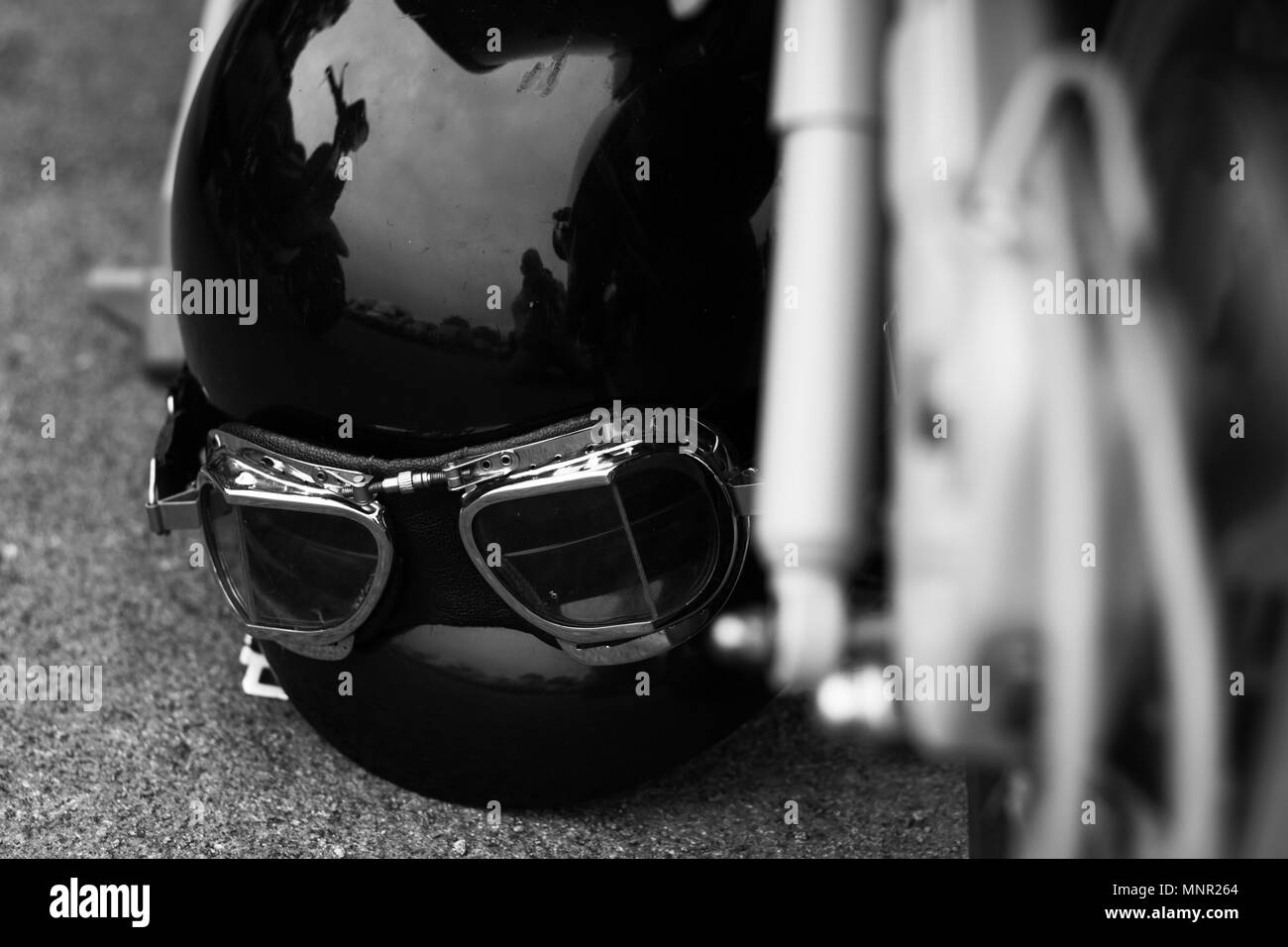 Oldtimer Motorrad Helm mit Brille auf dem Boden neben einem Scooter Stockfoto