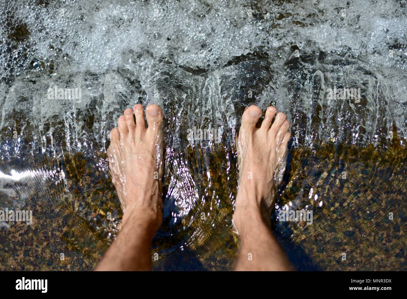 Wasser fließt durch eine natürliche Stream rund um die Personen, die Füße Stockfoto
