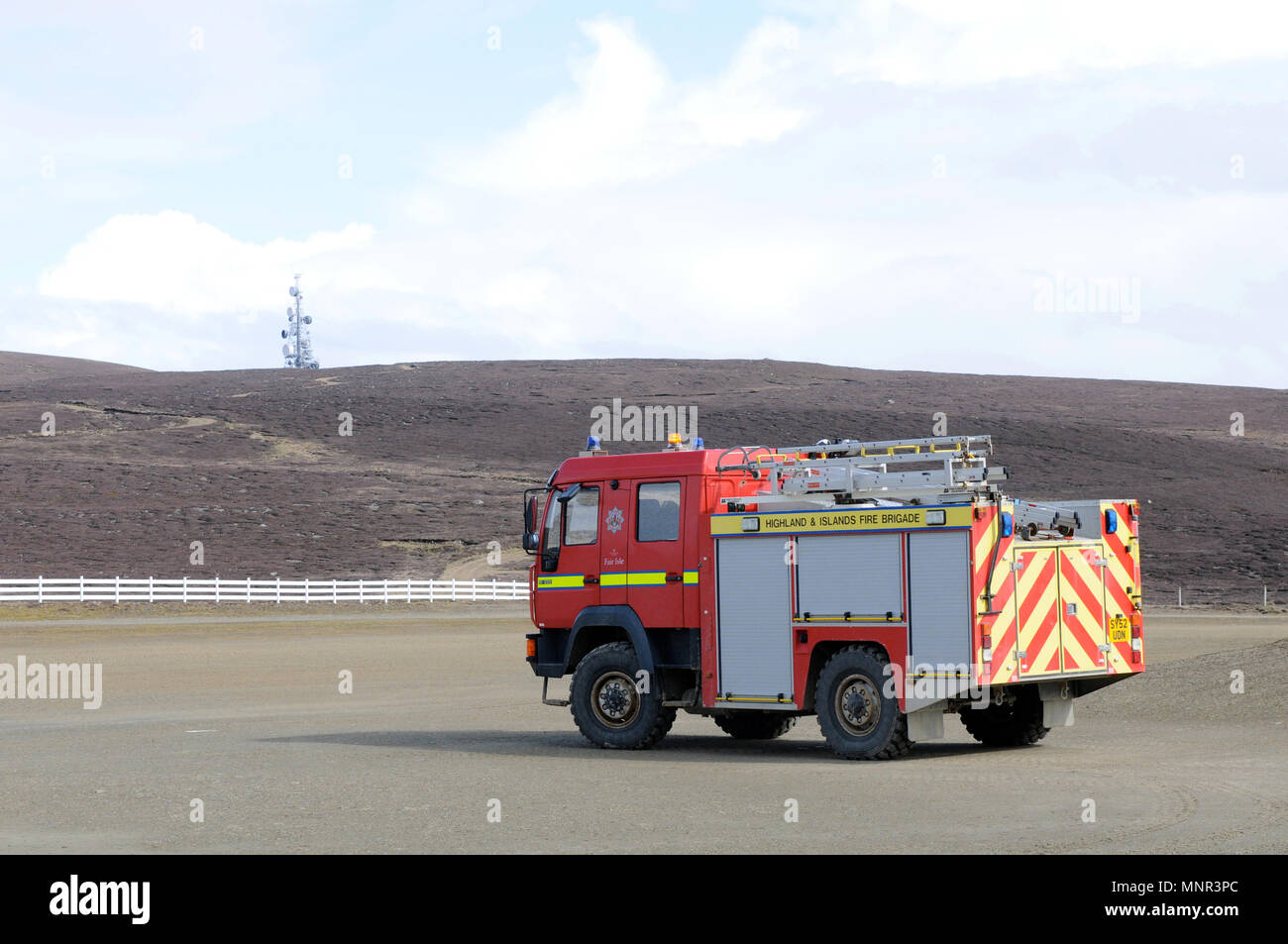 Feuerwehrauto auf der Landebahn auf dem Fair Isle Airstrip positioniert, was die Rettungsdienste auf dieser abgelegenen Shetland Insel hervorhebt. Stockfoto