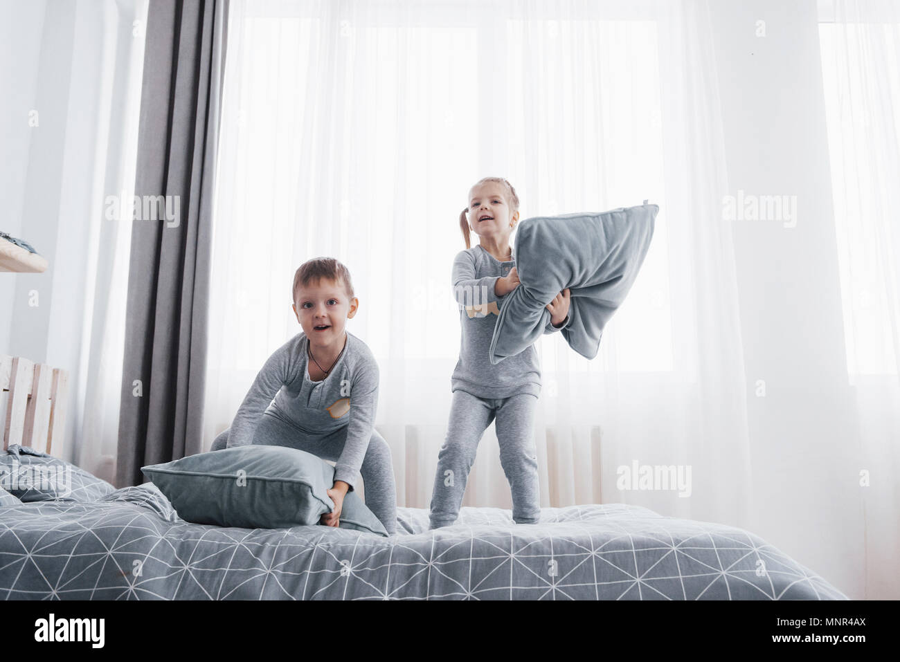 Kinder Im Bett Der Eltern Kinder Aufwachen Im Sonnigen Weissen Schlafzimmer Junge Und Madchen Spielen In