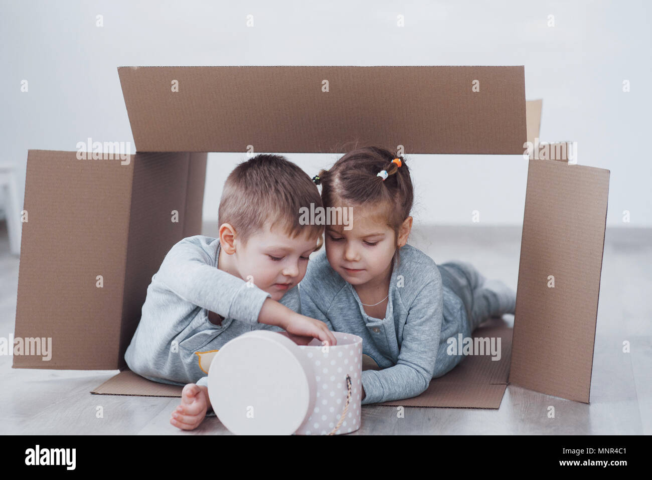 Zwei kleine Kinder, Junge und Mädchen spielen in Kartons. Konzept Foto. Kinder haben Spaß Stockfoto