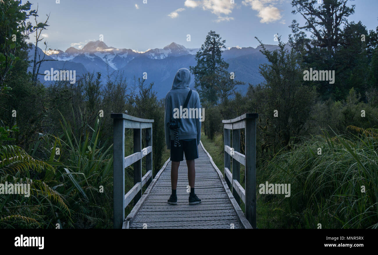 Ein Junge mit einer Kamera mit Blick auf die Landschaft in der Morgendämmerung in Neuseeland Stockfoto