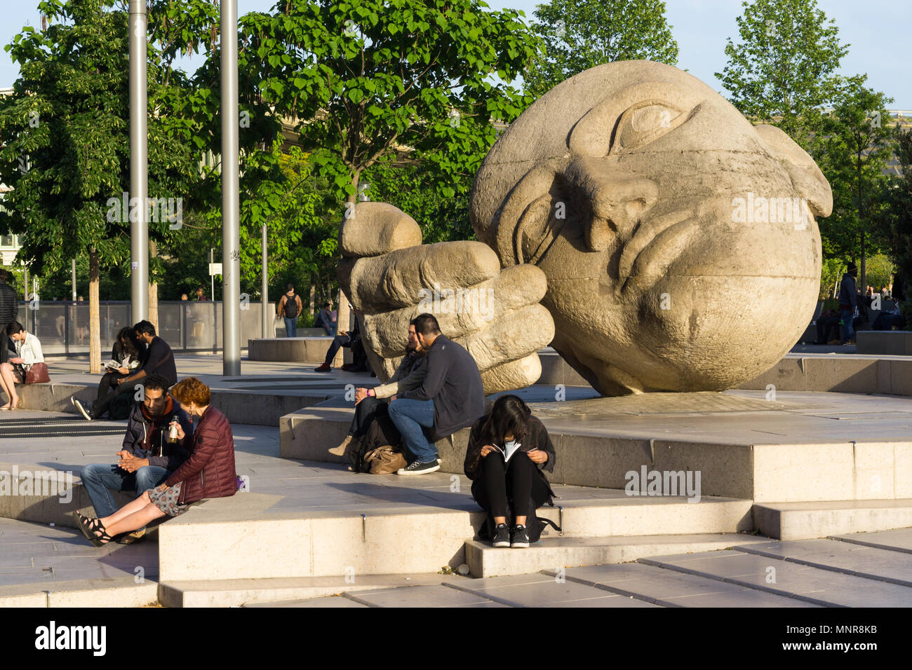 Menschen sitzen in der Nähe der Skulptur Ecoute (hören) von Henri de Miller in Paris, Frankreich. Stockfoto