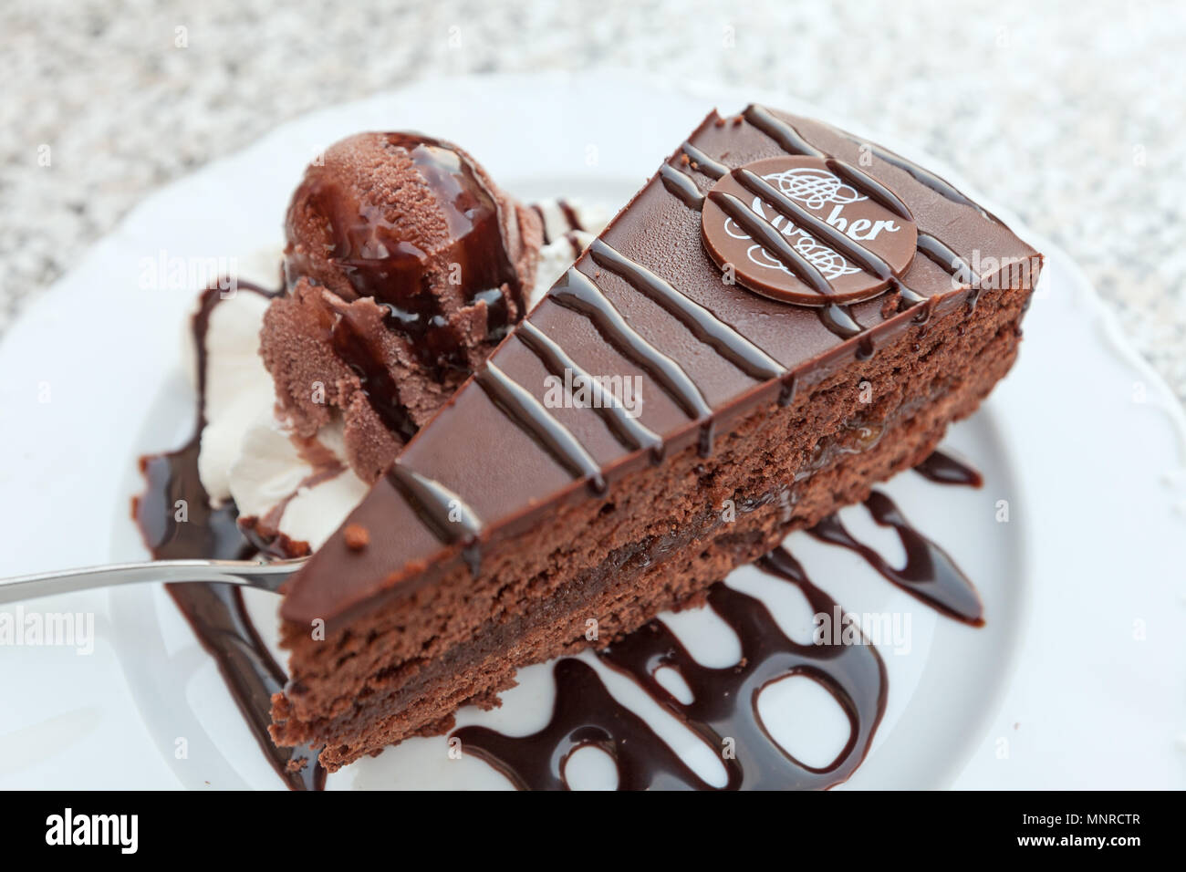 Schokoladenkuchen im Stil der Sachertorte plus eine Kugel aus Schokolade, Eis Stockfoto