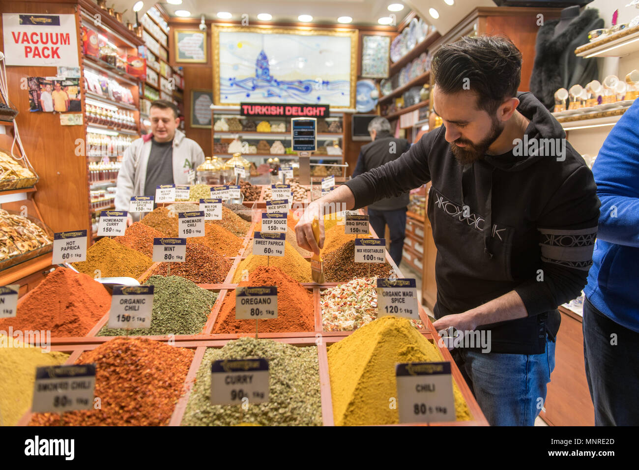 Männliche Kaufmann verwendet Pinsel überschüssige Gewürze aus der Container in seiner Spice Shop in Istanbul, Spice Bazaar in der Türkei ordentlich Stockfoto