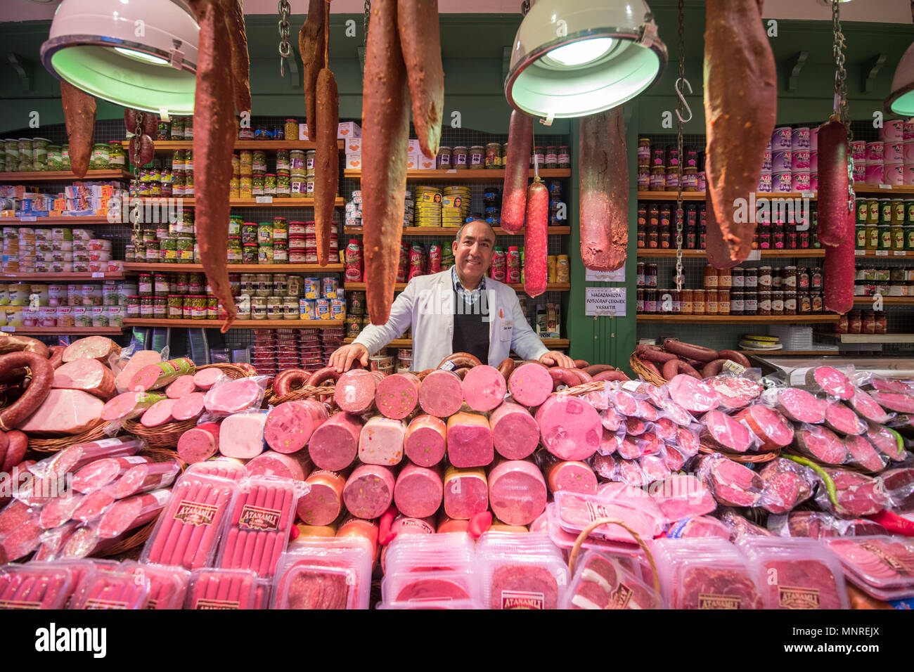 Ein lächelndes Männchen Kaufmann steht hinter Zähler mit verschiedenen Arten von Fleisch zum Verkauf in Istanbul, Spice Bazaar in der Türkei Stockfoto