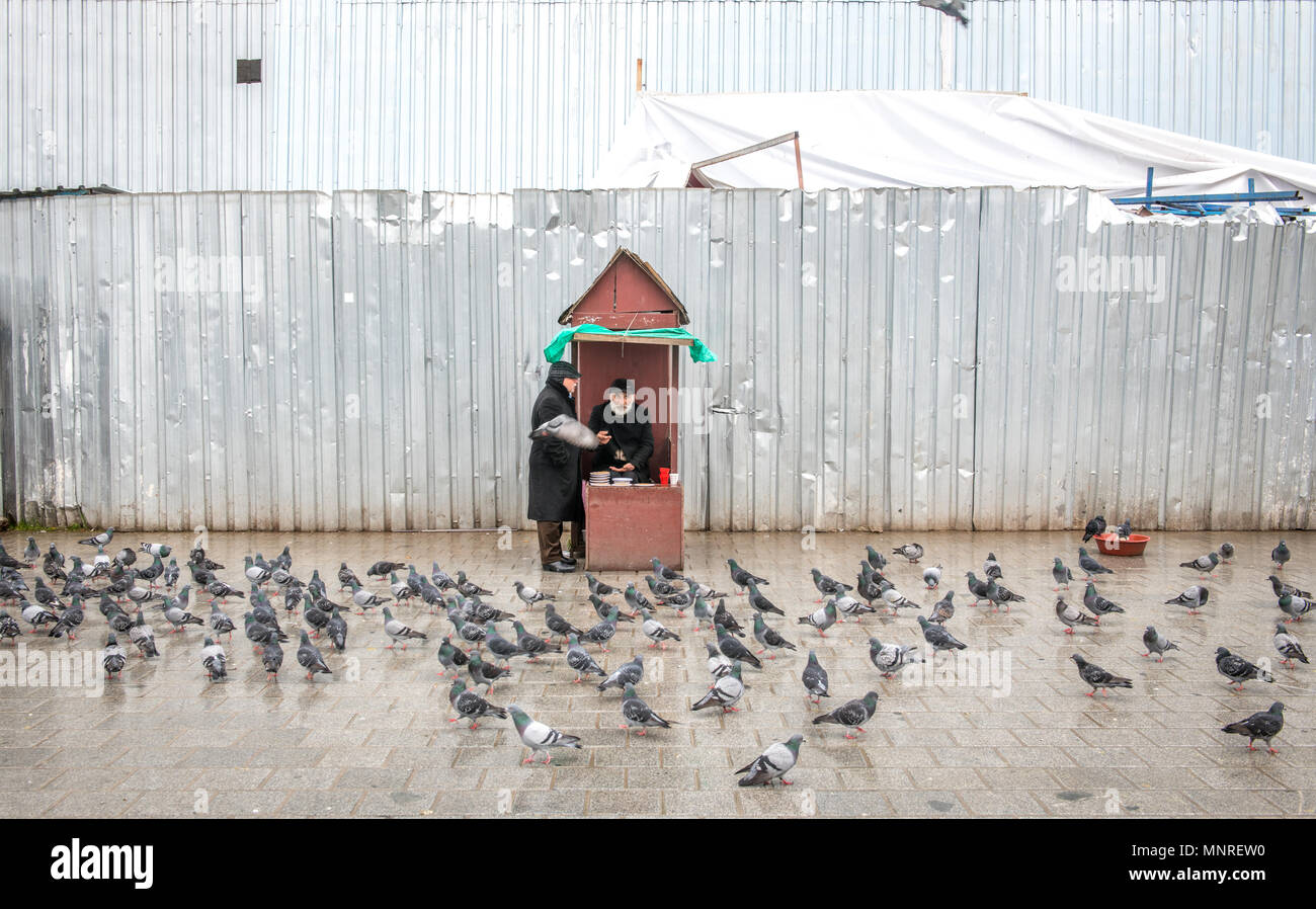 Zwei erwachsene Männchen converse außerhalb beim Füttern Tauben an einem regnerischen Tag in Istanbul, Türkei. Stockfoto