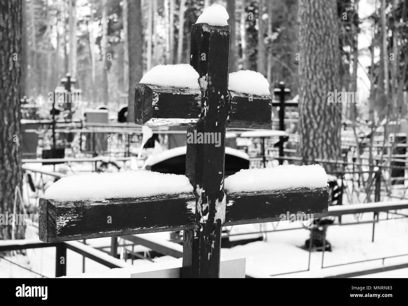 Schwarz-weiß Bild von einer alten hölzernen Kreuz bedeckt mit Schnee auf dem Grab eines orthodoxen Friedhof im Winter Stockfoto