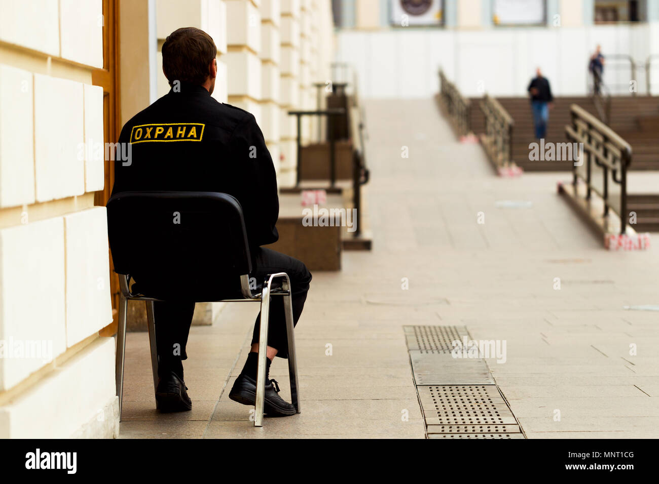 Wachmann saß auf einem Stuhl an der Tür im Zimmer, Tageslicht Stockfoto