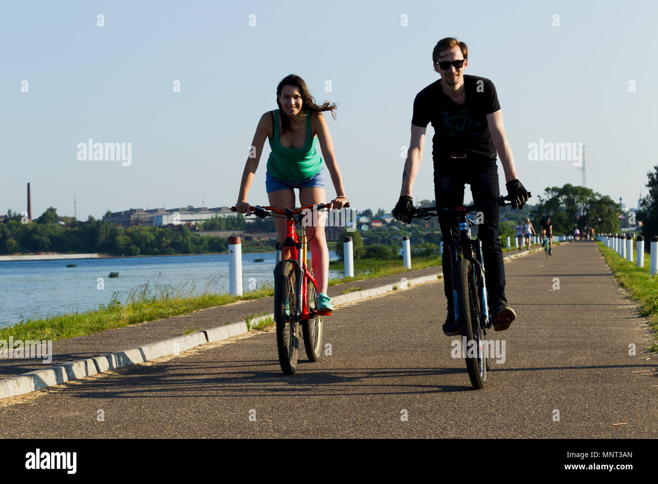 Das Mädchen und der junge Mann auf einem Fahrrad in der Stadt, beleuchtet durch Sonnenlicht Stockfoto