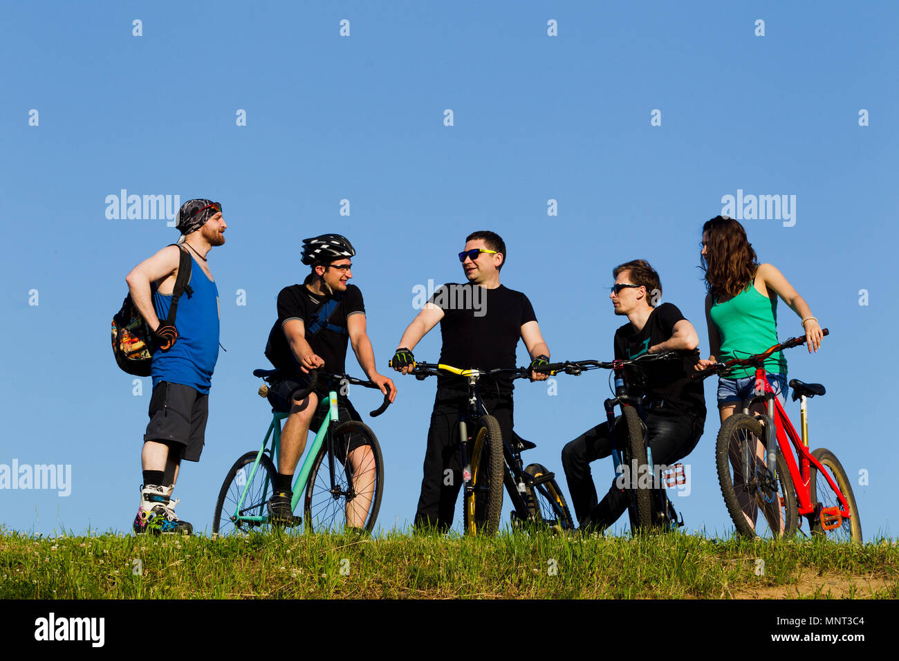 Gruppe von jungen Menschen, ein Mann und ein Mädchen auf einem Fahrrad in der Stadt, beleuchtet durch Sonnenlicht Stockfoto