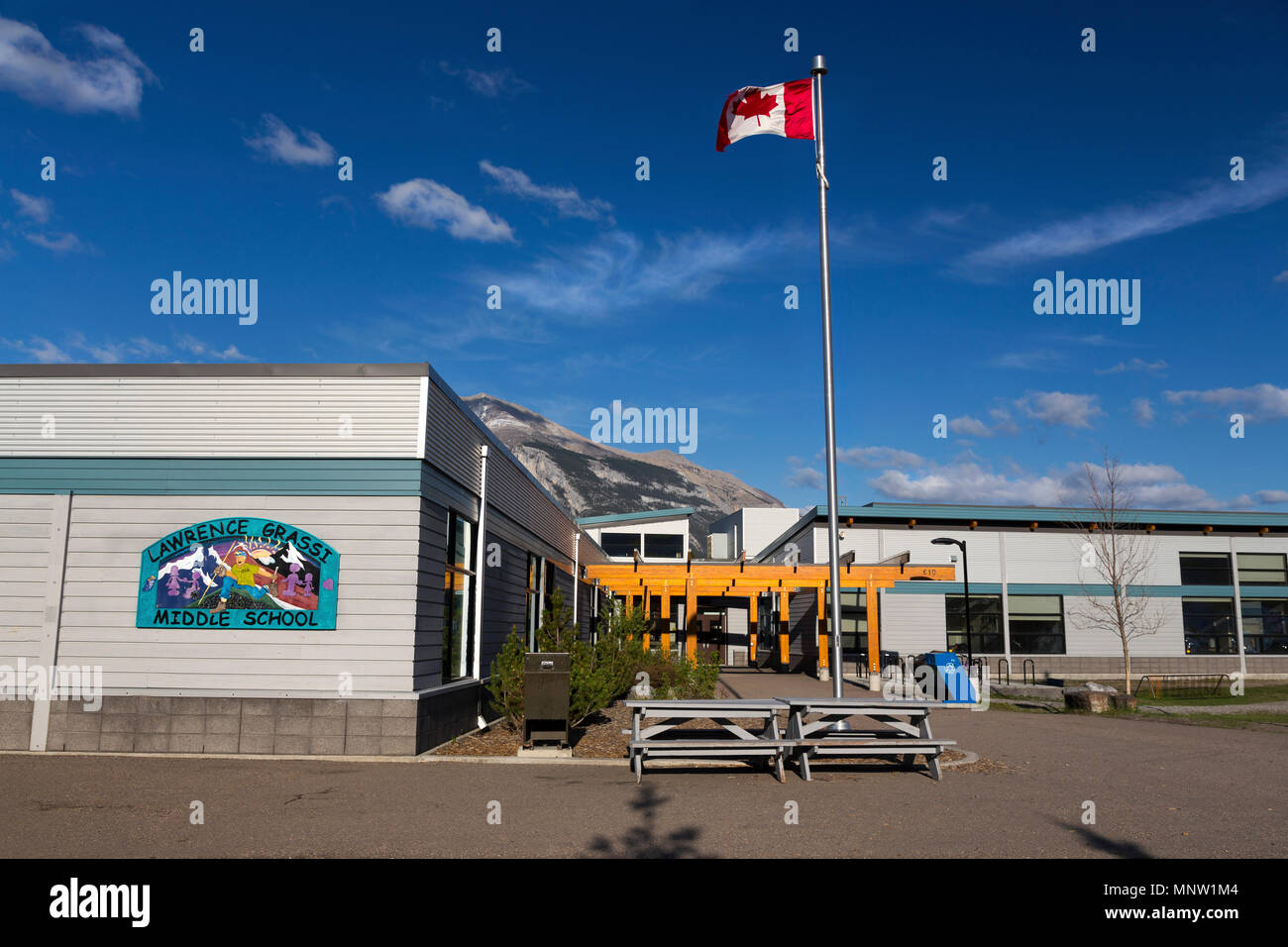 Lawrence Grassi Middle School Gebäude Exterieur mit der kanadischen Flagge und fernen Rocky Mountains in Canmore, Alberta Stockfoto