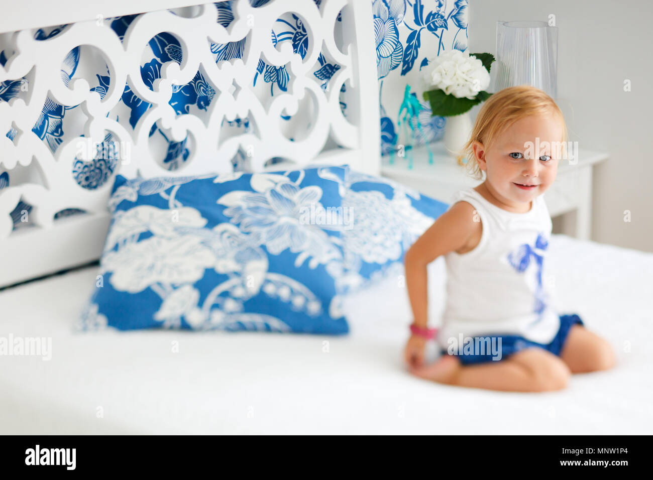 Portrait von adorable lächelnd Kleinkind Mädchen sitzt auf dem Bett, schön eingerichtete Schlafzimmer Stockfoto