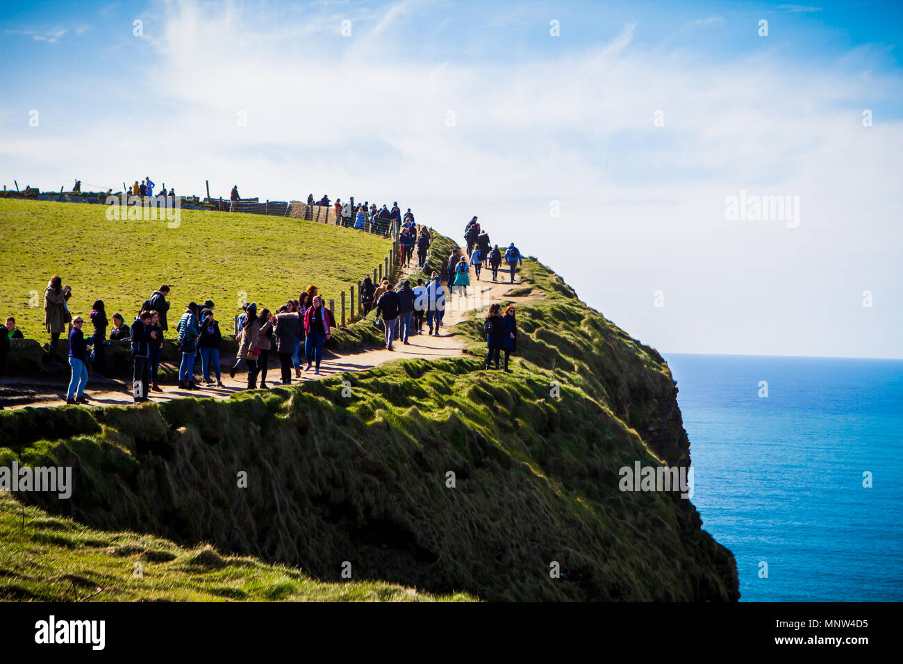 Touristen auf den Klippen von Moher an einem sonnigen Tag in der Grafschaft Clare, Irland Stockfoto