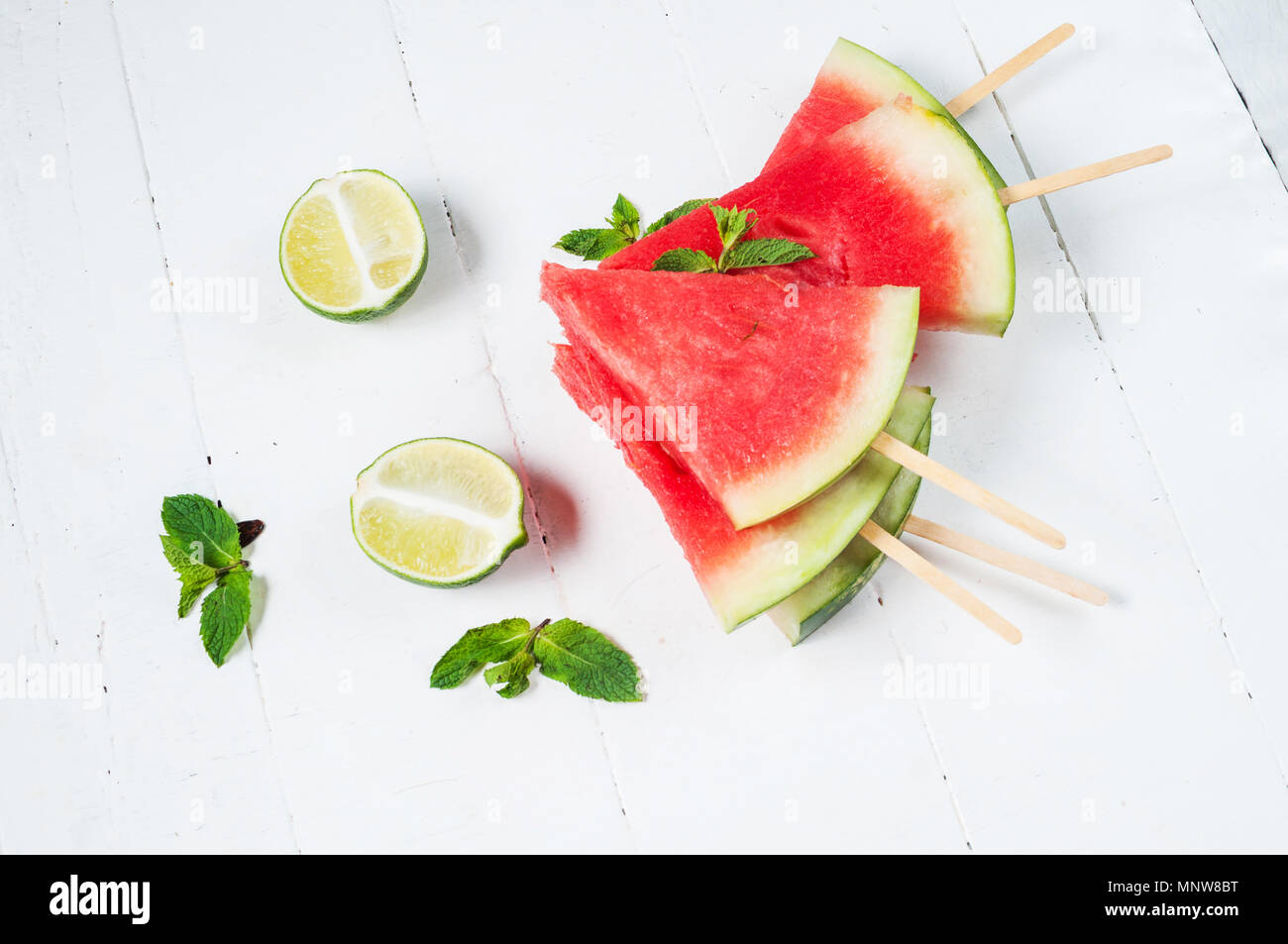 Wassermelone Schicht Eis am Stiel und Kalk auf rustikalem Holz Hintergrund. Stockfoto