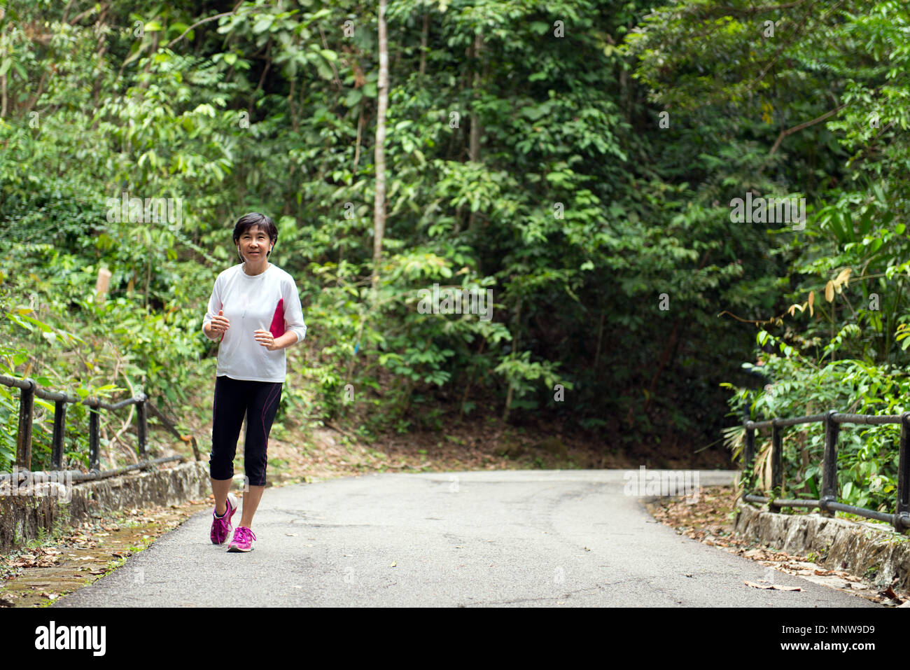 Vorderansicht der älteren Frau joggen durch den Park Stockfoto