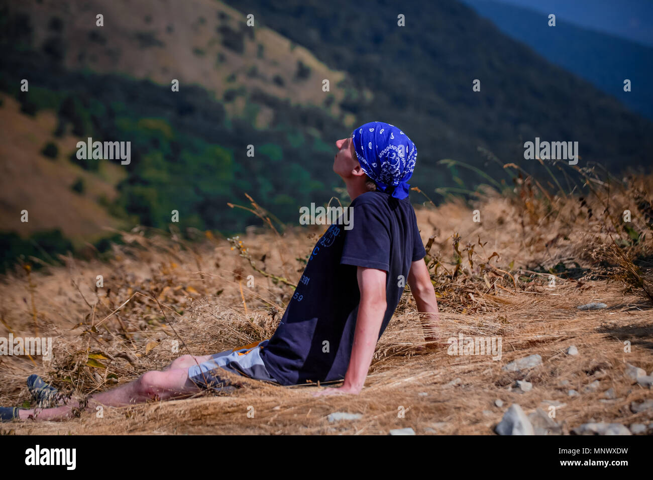 Junge tourist Guy sitzt auf einem hohen Berg und die Aussicht genießen. Stockfoto