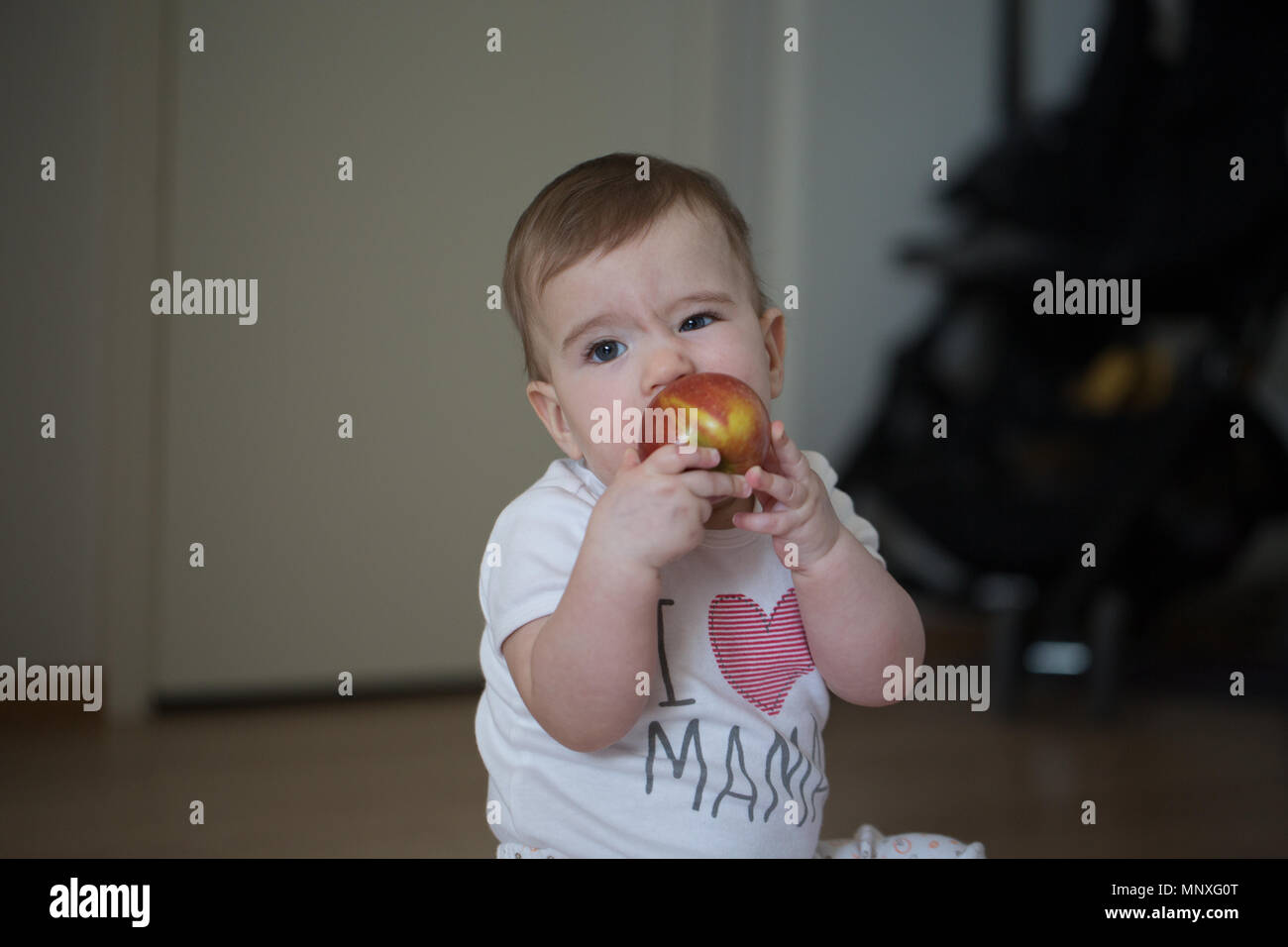 Kleines Kind hält seine Hände apple und nagt Stockfoto