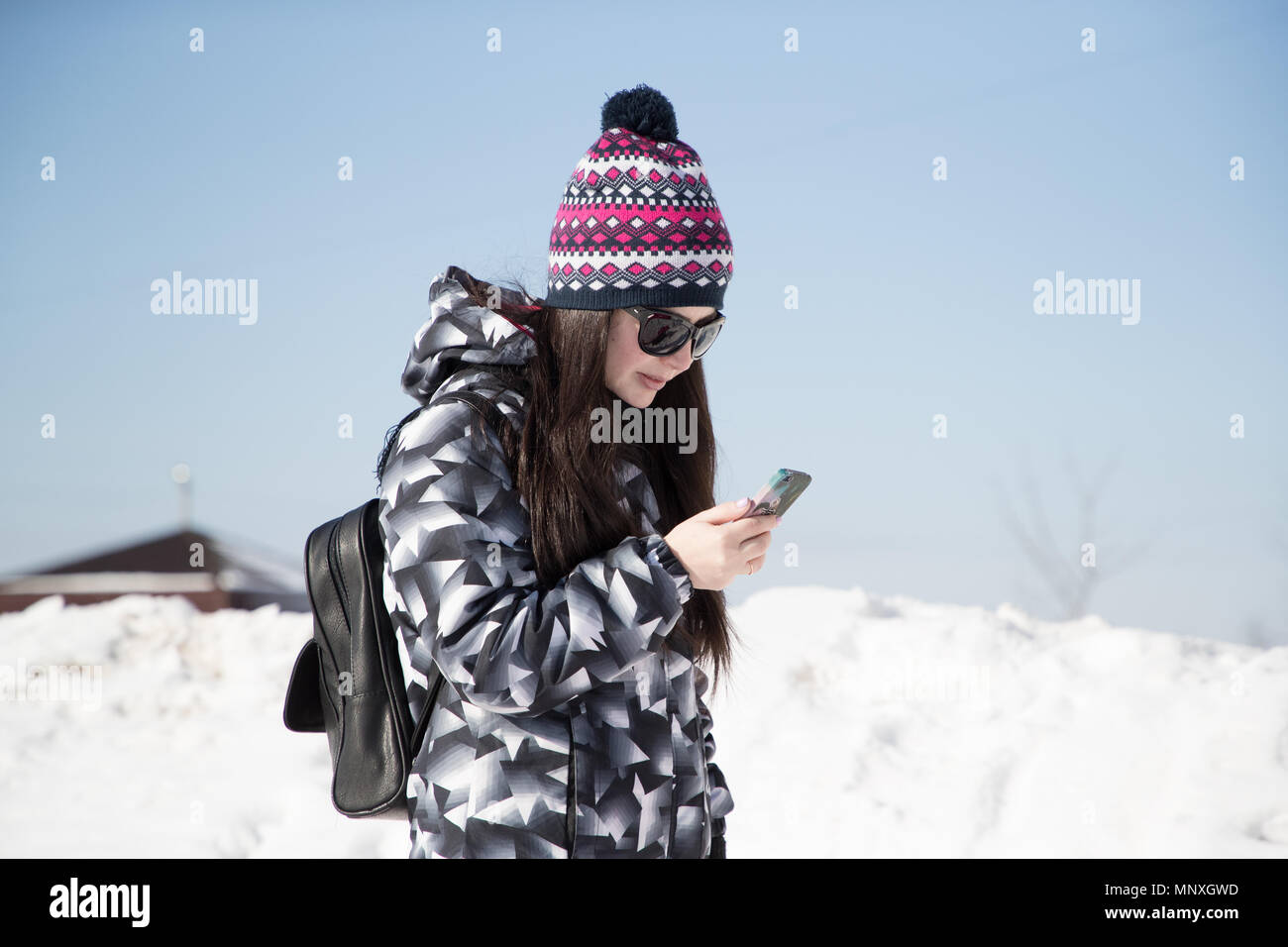 Mädchen in der Sonnenbrille im Winter auf der Straße ihr Telefon Holding Stockfoto