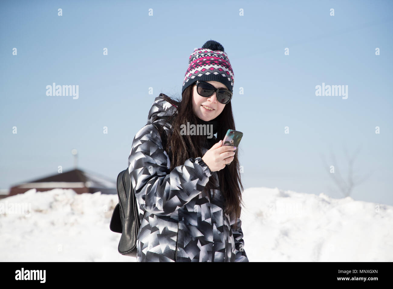 Mädchen in der Sonnenbrille im Winter auf der Straße ihr Telefon Holding Stockfoto