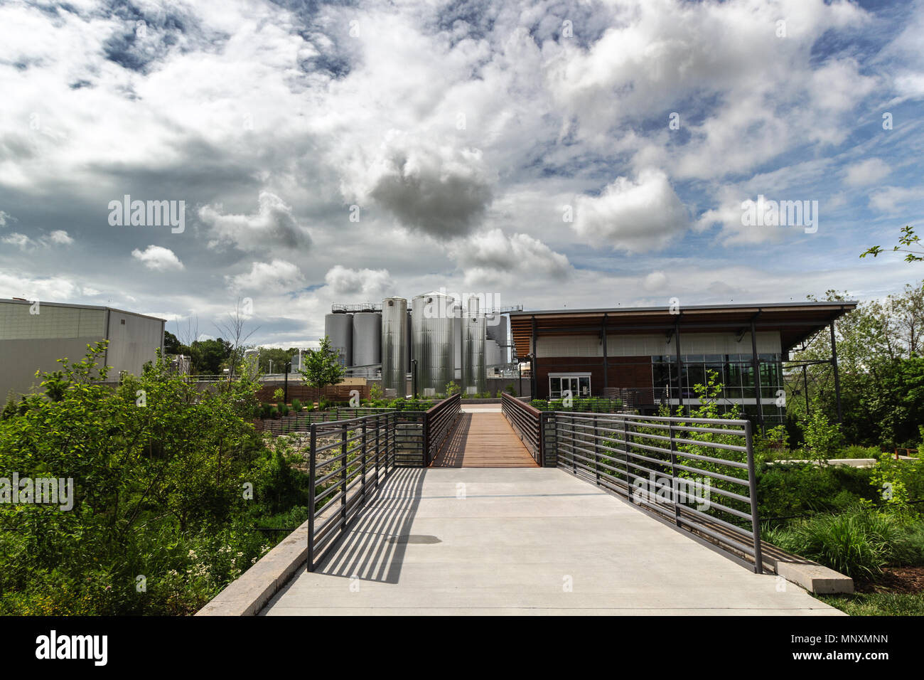 Ein Fußweg führt zum sudhaus an der New Belgium Brewing Company in Asheville, NC, USA, mit dramatischen Wolken über es. Stockfoto